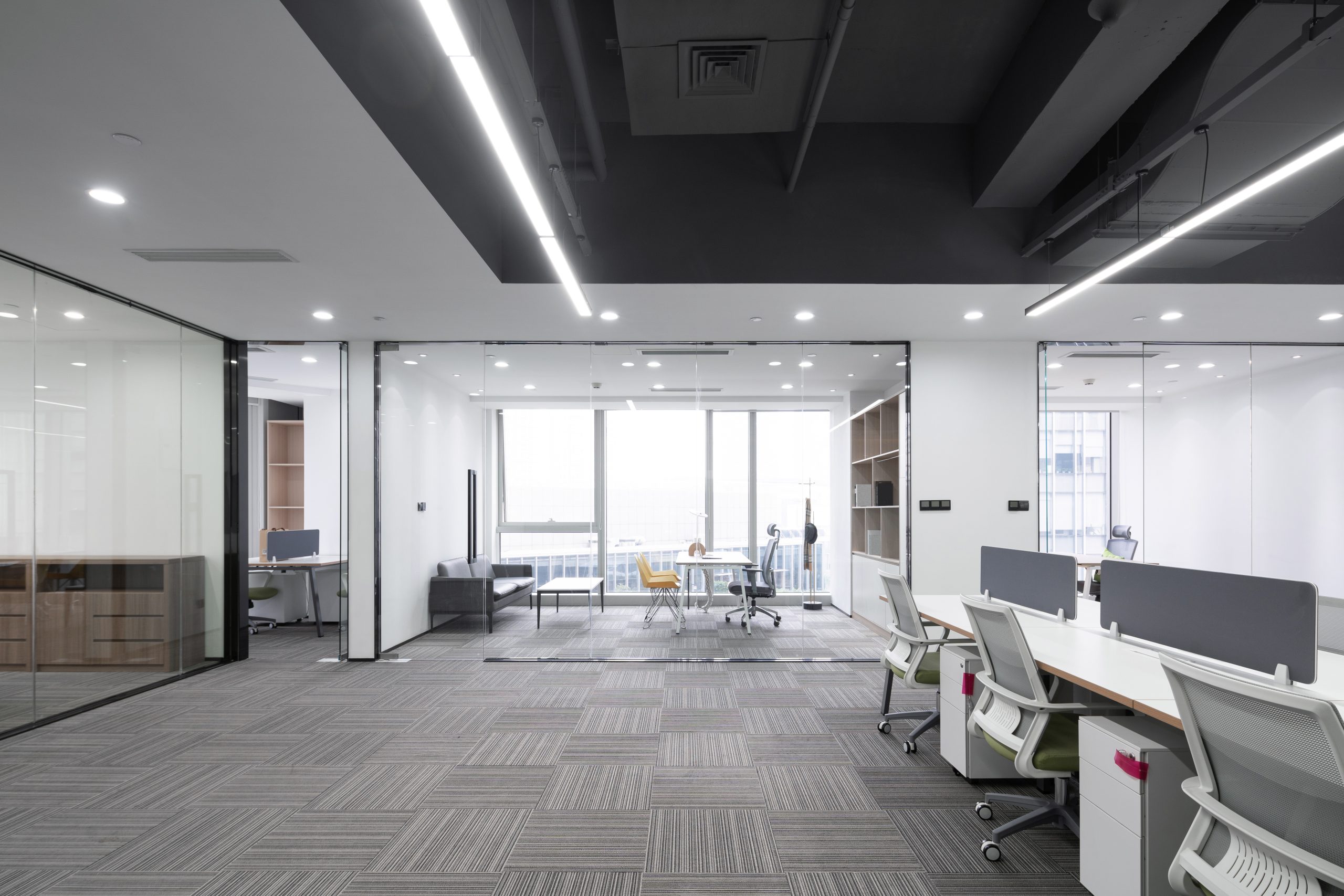 Modern small business office with desks, ergonomic chairs and glass meeting room